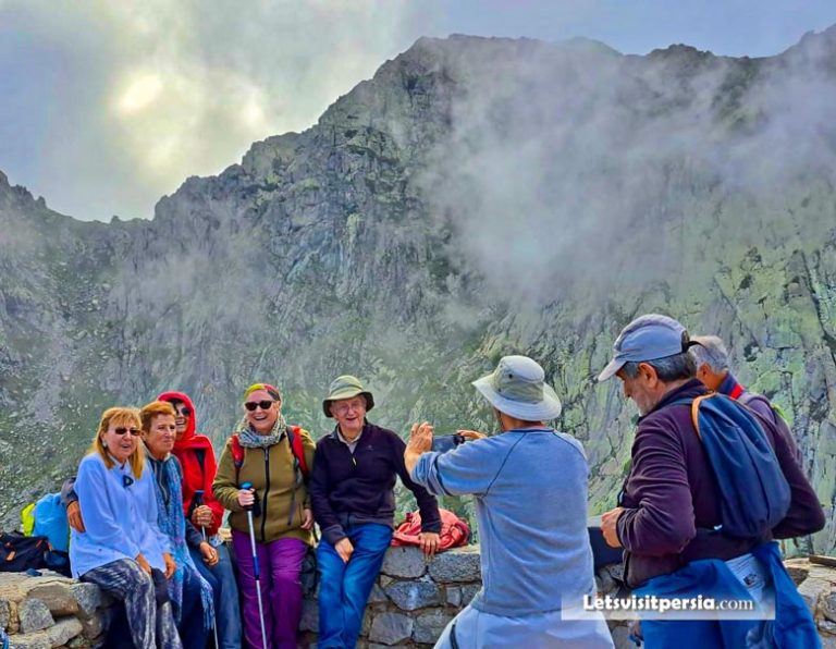 Taking a group photo of tourists at a natural historical attraction in Iran.