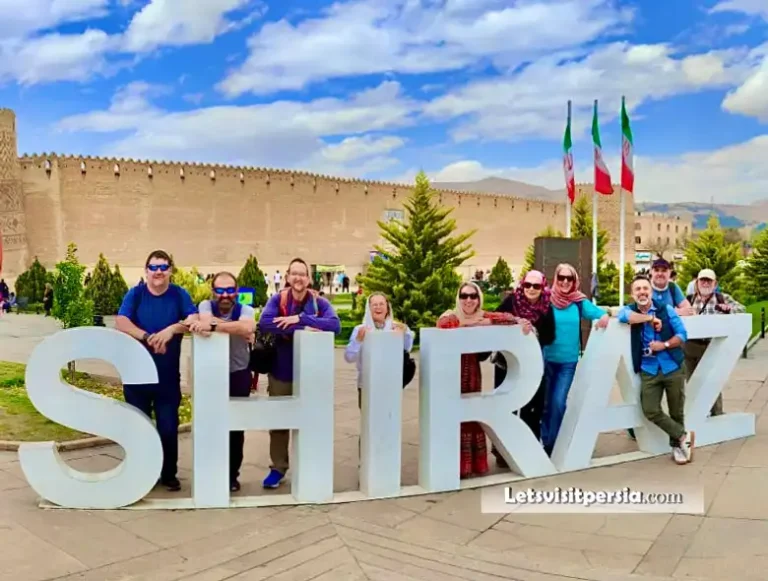 Tourists posing with “Shiraz” sign in front of Karim Khan Citadel